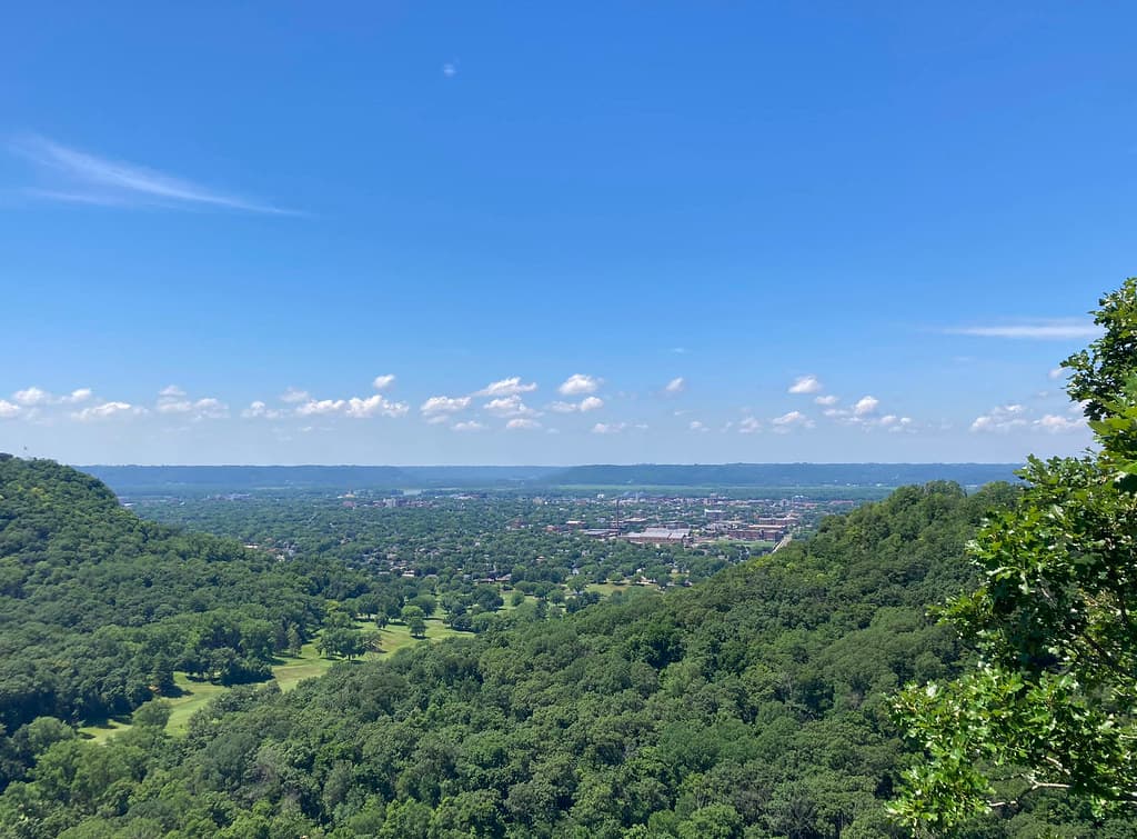 Bluffland forest and the city of La Crosse beneath a clear blue sky