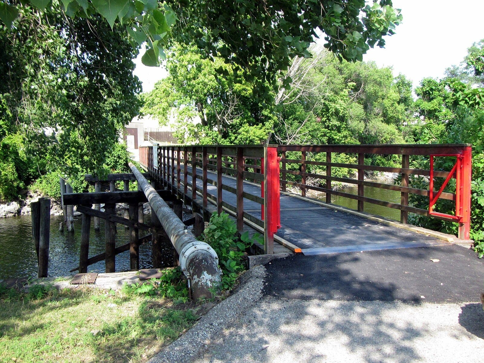 Empty footbridge crossing a wooded river channel in Houska Park